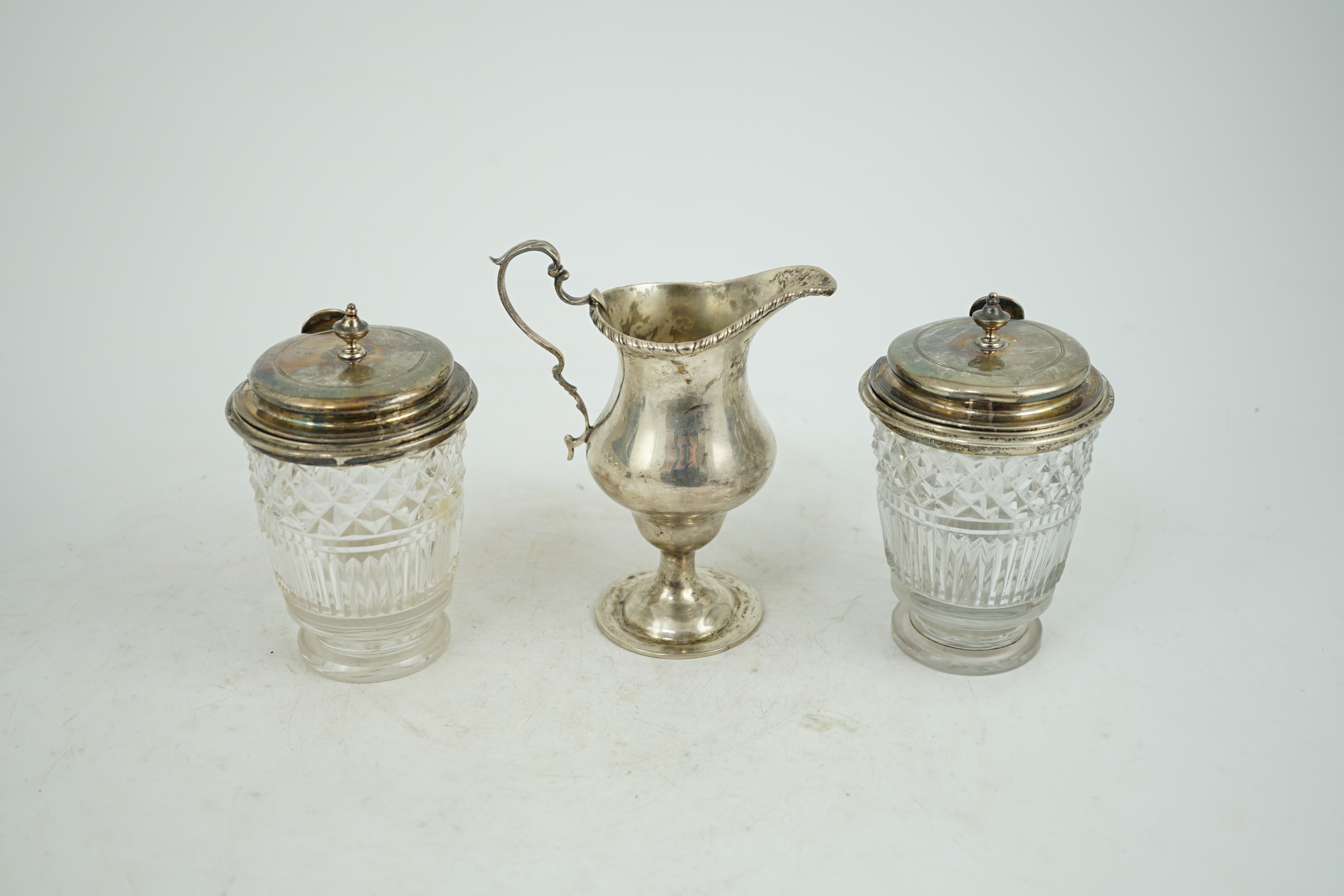 Two George III silver mounted glass cruet bottles, London, 1808, height 12.6cm and a late Victorian silver inverted pear shaped cream jug.